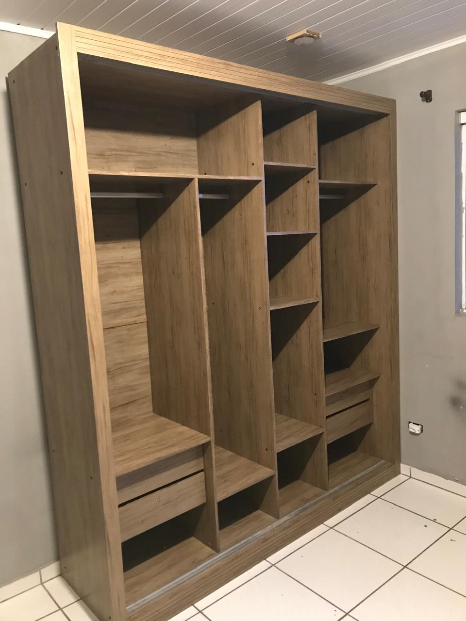 Interior de guarda-roupa em madeira com nichos e gavetas montado profissionalmente